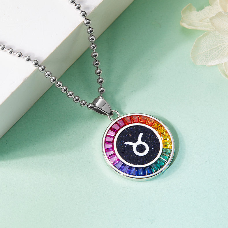 Necklace with a colorful pendant featuring a zodiac symbol on a light green surface.