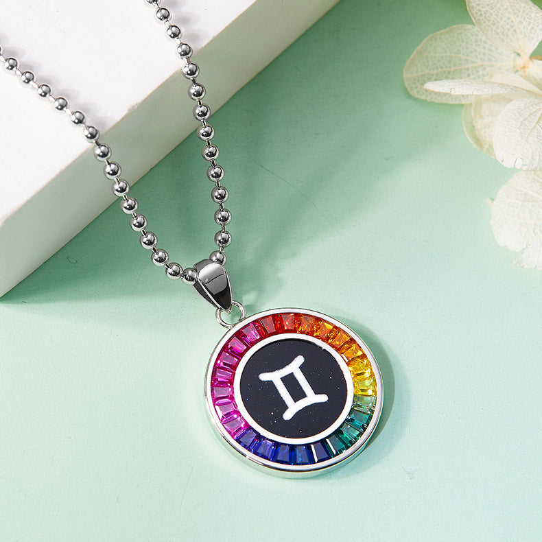 Necklace with a Gemini zodiac sign pendant featuring a rainbow-colored border on a light green background.