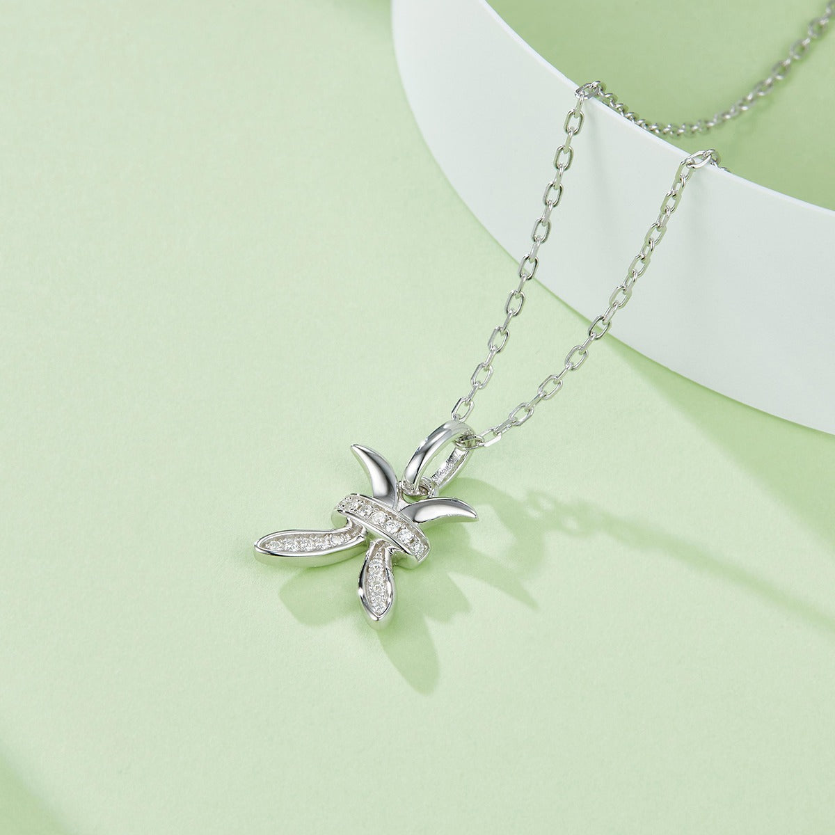Silver necklace with a Pisces Zodiac Pendant on a light green background