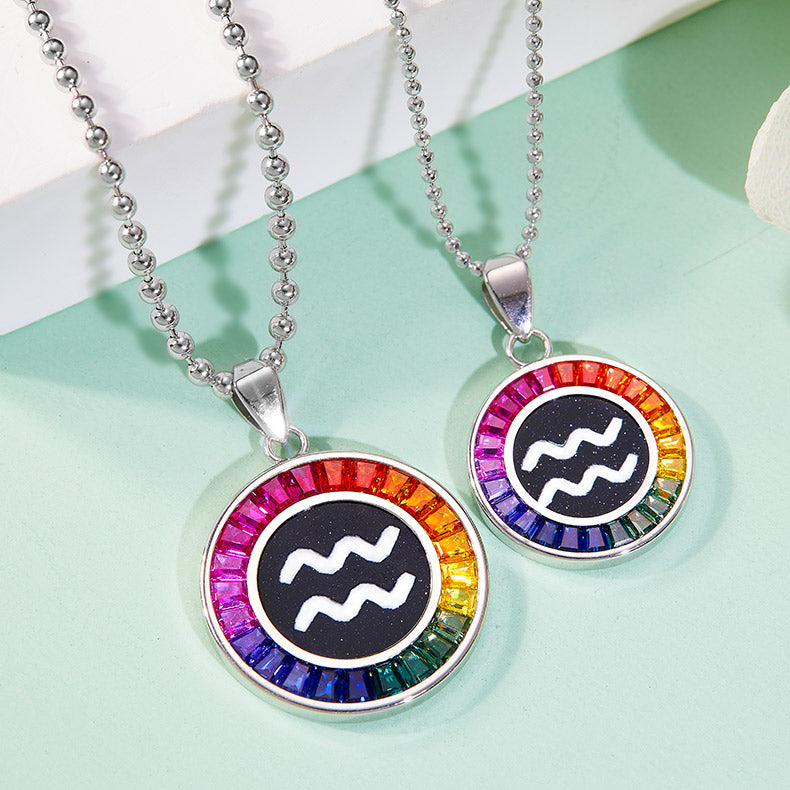 Two Aquarius zodiac symbol necklaces with rainbow-colored stones on a light green background.
