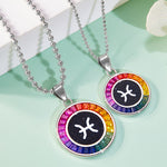 Two zodiac symbol necklaces with colorful bead accents on a light green surface.