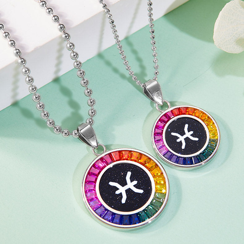 Two zodiac symbol necklaces with colorful bead accents on a light green surface.