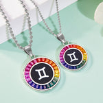 Two zodiac necklaces with rainbow-colored stones on a light green background