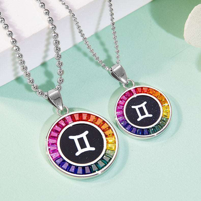 Two zodiac necklaces with rainbow-colored stones on a light green background