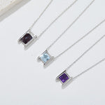Three silver necklaces with square gemstones on a white background