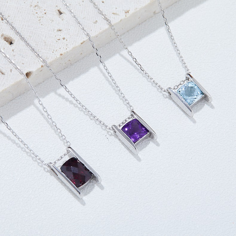 Three silver necklaces with rectangular gemstones on a light background