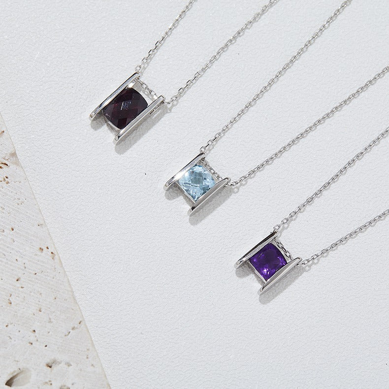 Three silver necklaces with gemstone pendants on a white background