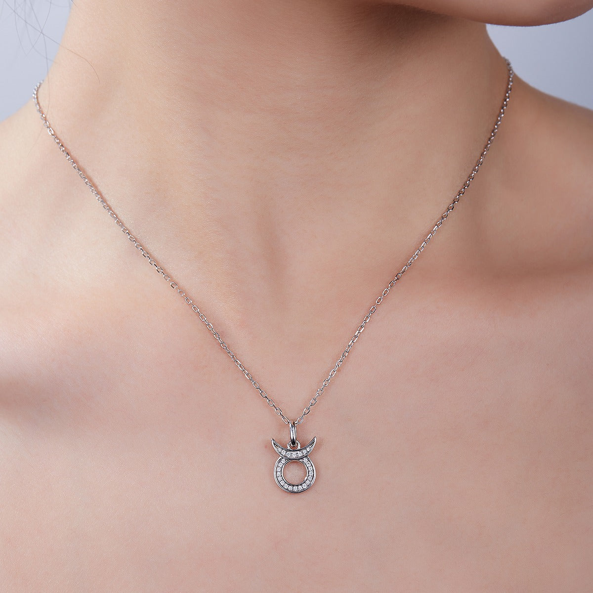 Silver necklace with a Taurus zodiac pendant on a model's neck