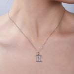 Silver necklace with a Gemini pendant on a neutral background