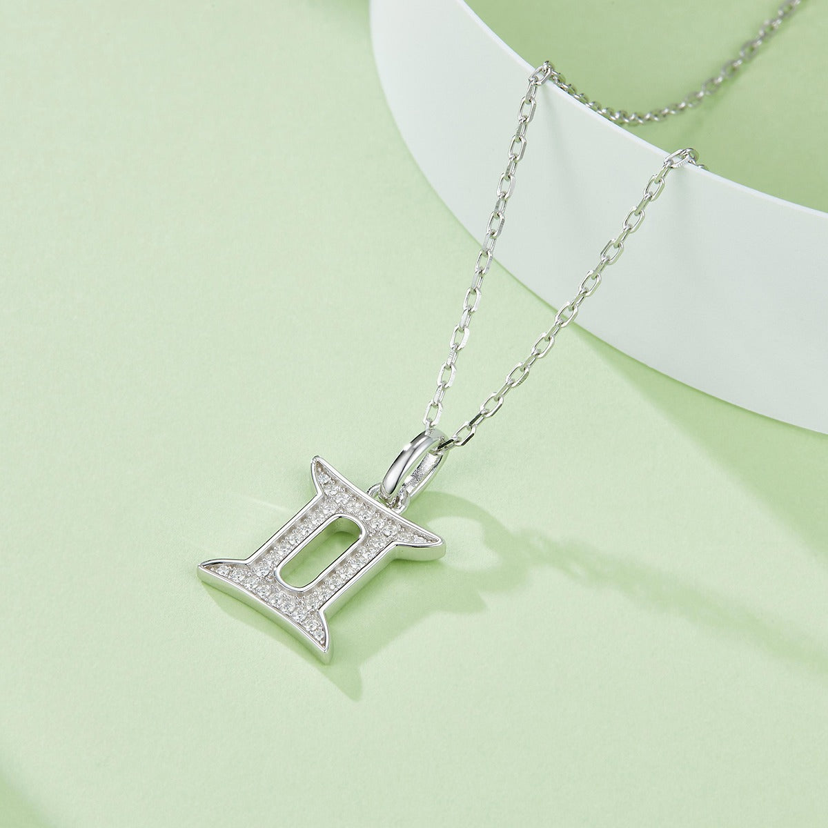 Silver necklace with a star-shaped pendant on a light green background