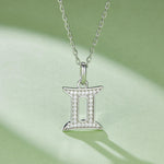 Silver Gemini zodiac pendant necklace on a light green background