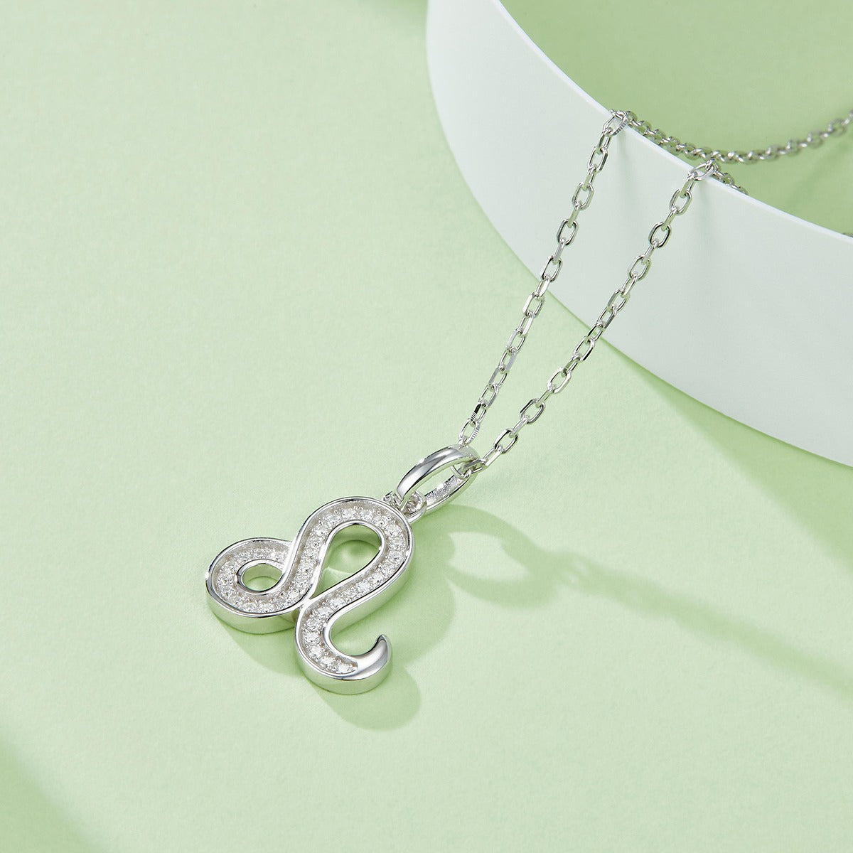 Silver snake-shaped pendant necklace on a light green background