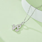 Silver necklace with a 'WJ' pendant on a light green background