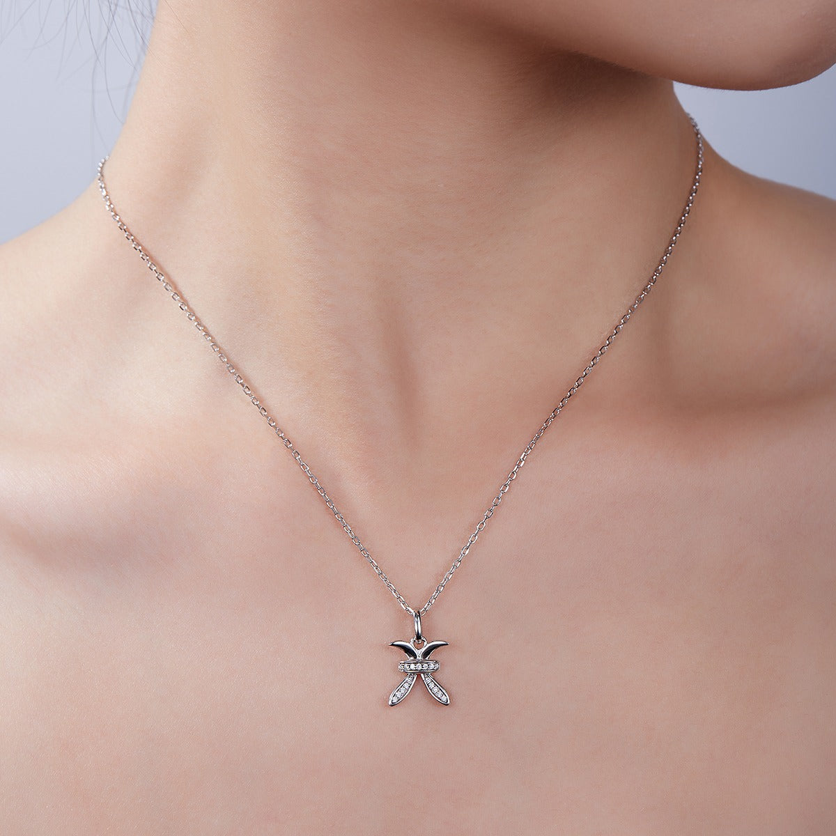 Silver necklace with a Pisces Zodiac Pendant on a model against a neutral background
