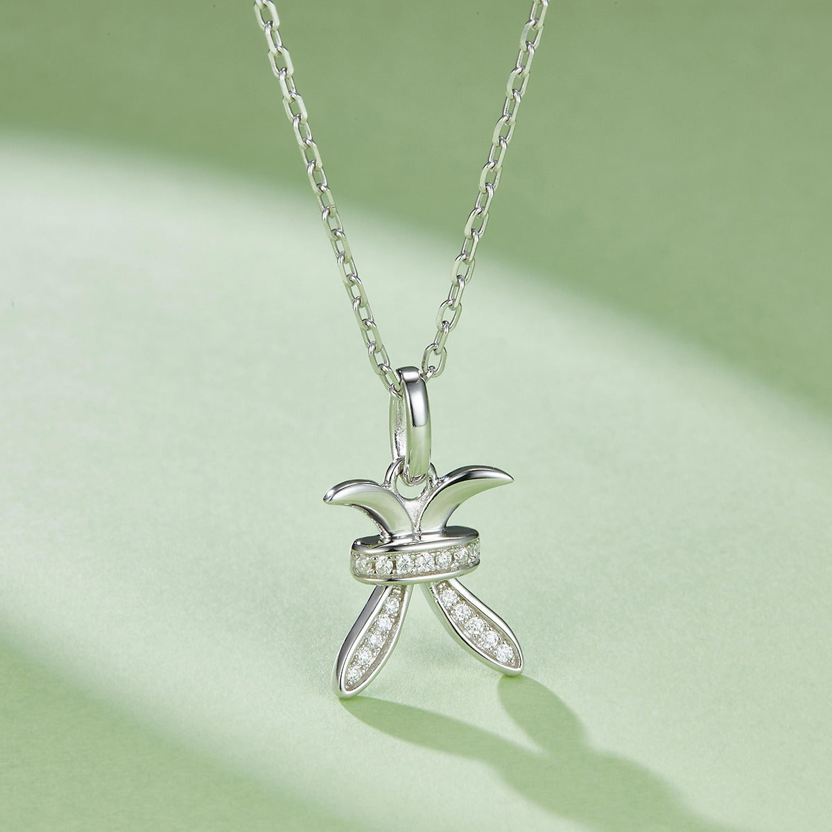 Silver necklace with a Pisces Zodiac Pendant on a light green background