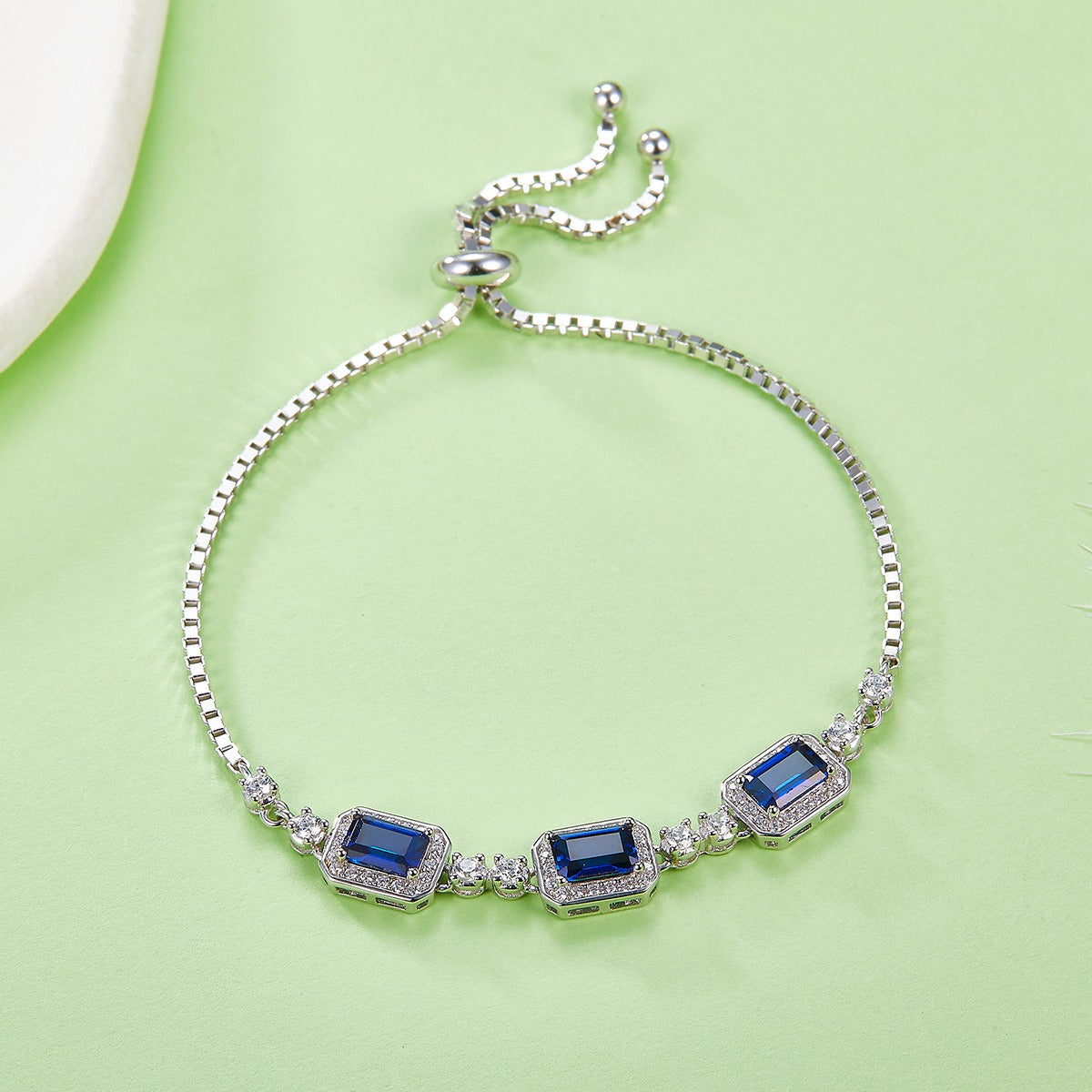 Silver bracelet with blue sapphire gemstones on a light green background