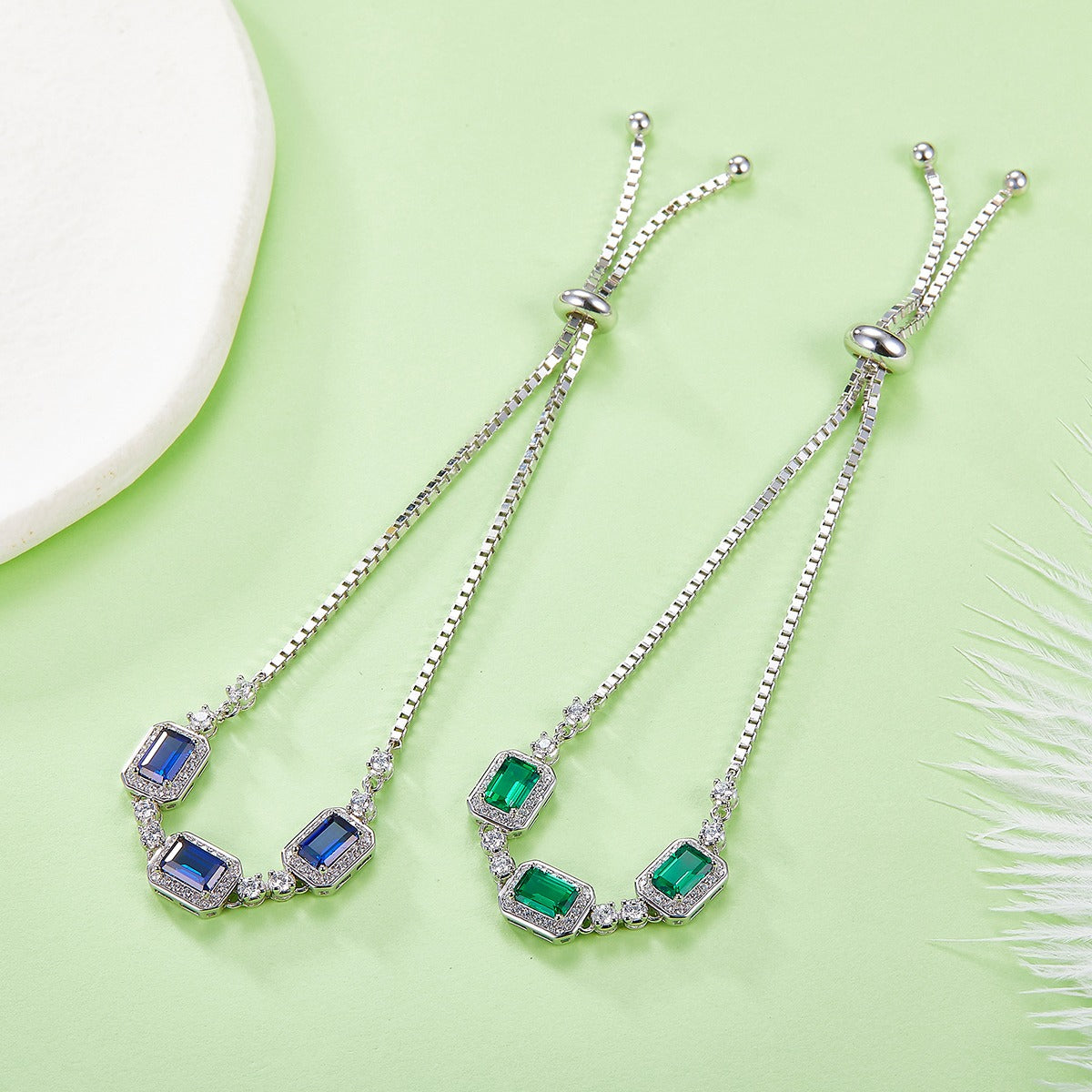 Two silver necklaces with gemstones on a light green background