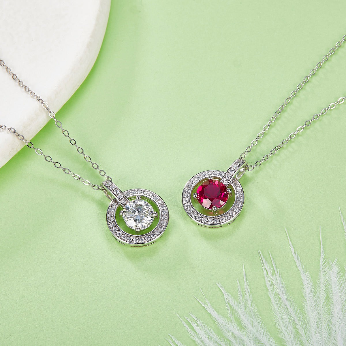 Two silver necklaces with gemstones on a green background