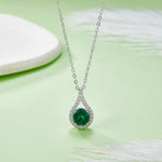Silver necklace with a green gemstone pendant on a light green background