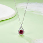 Silver necklace with a red gemstone pendant on a light green background