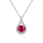 Teardrop-shaped pendant with a red gemstone and diamond accents on a white background