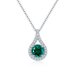 Teardrop-shaped pendant with green gemstone and diamond accents on a white background