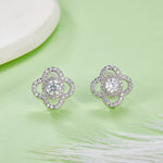 Silver floral earrings with clear gemstones on a light green background