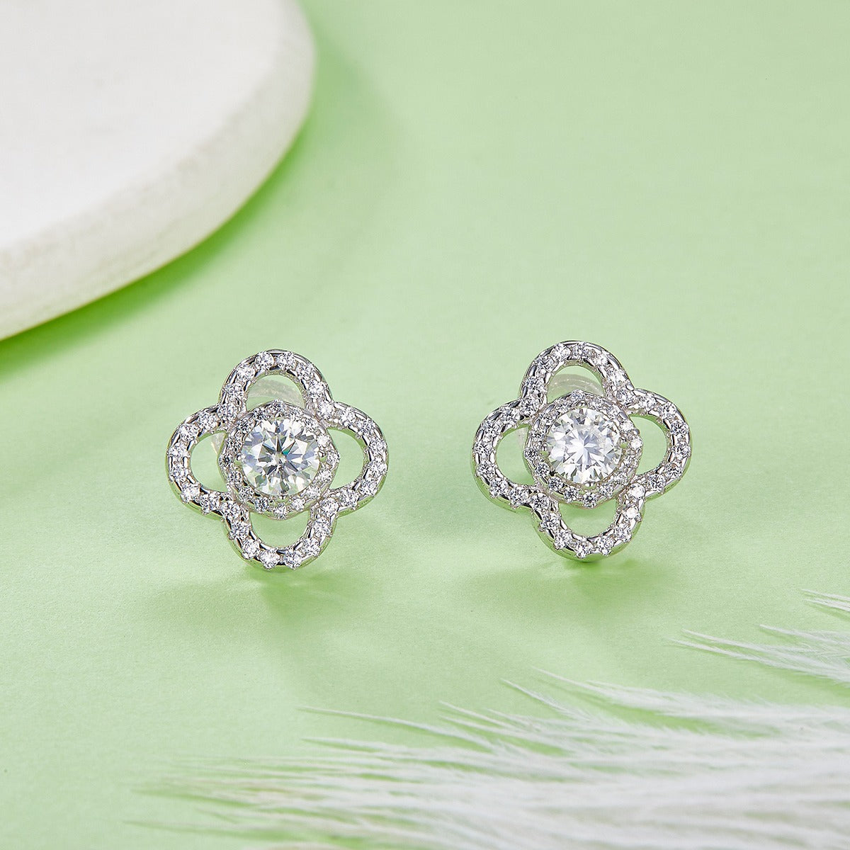 Silver floral earrings with clear gemstones on a light green background