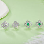 Four pairs of earrings with green emerald gemstones on a light green background