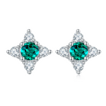 Pair of earrings with emerald gmstones and diamond-like stones on a white background 
