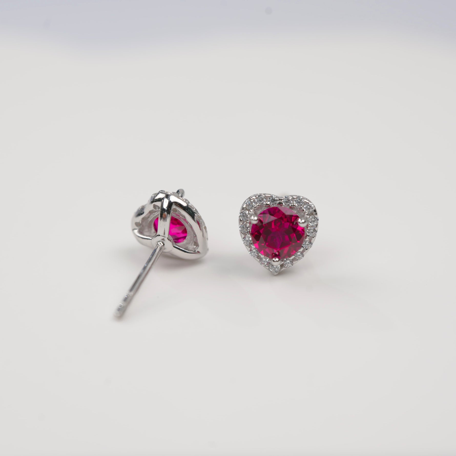 Heart-shaped red gemstone earrings on a white background