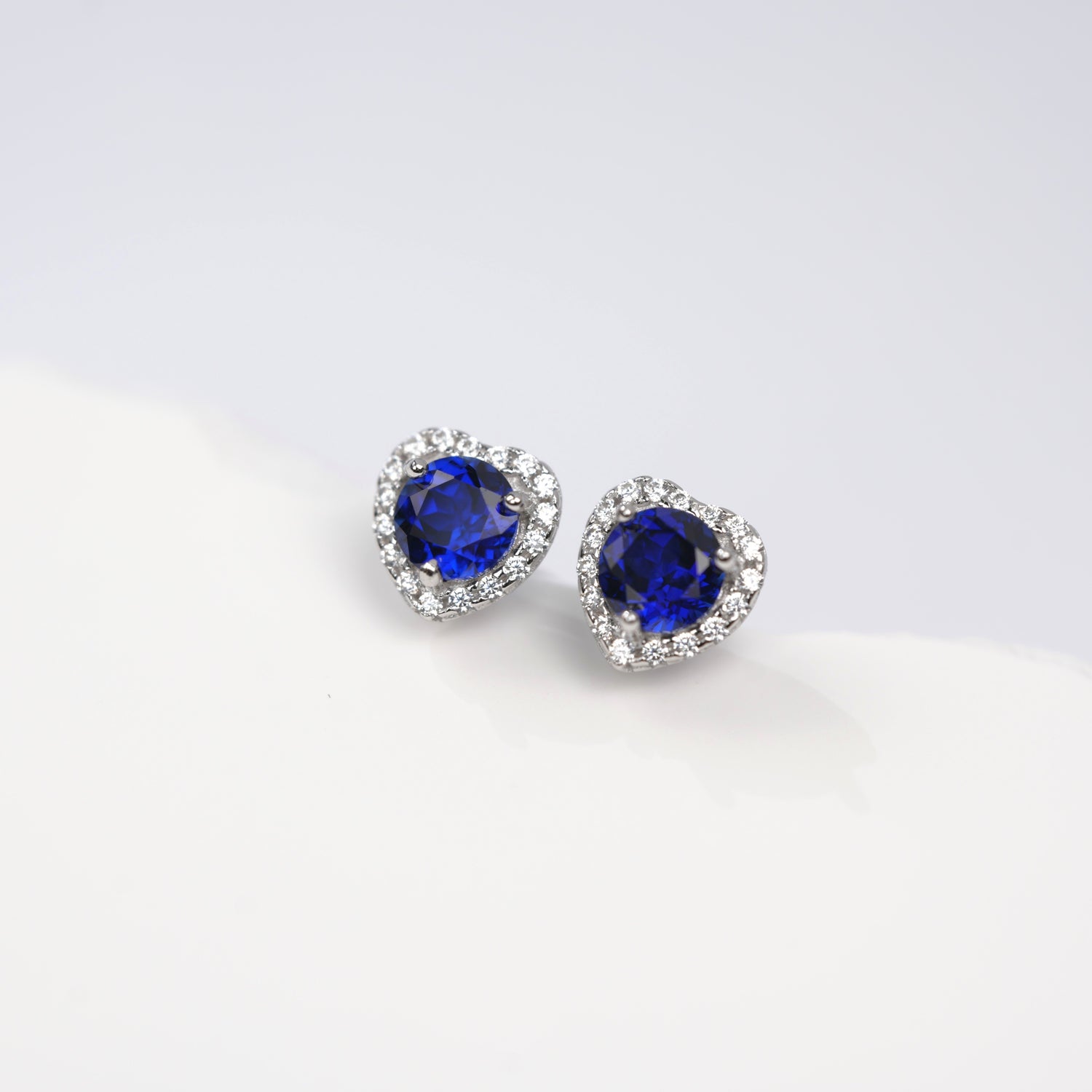 Heart-shaped blue gemstone earrings on a white background