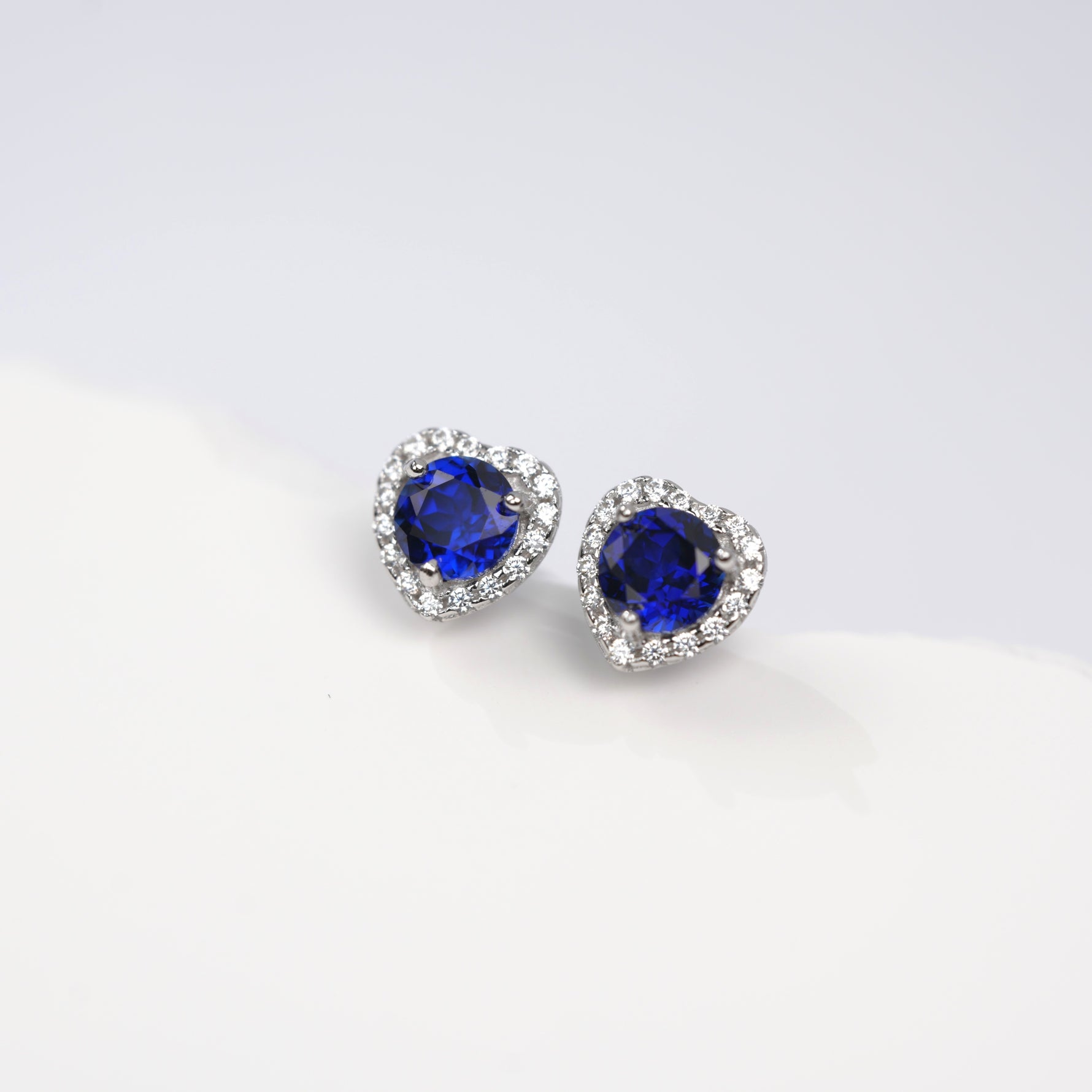 Heart-shaped blue gemstone earrings on a white background