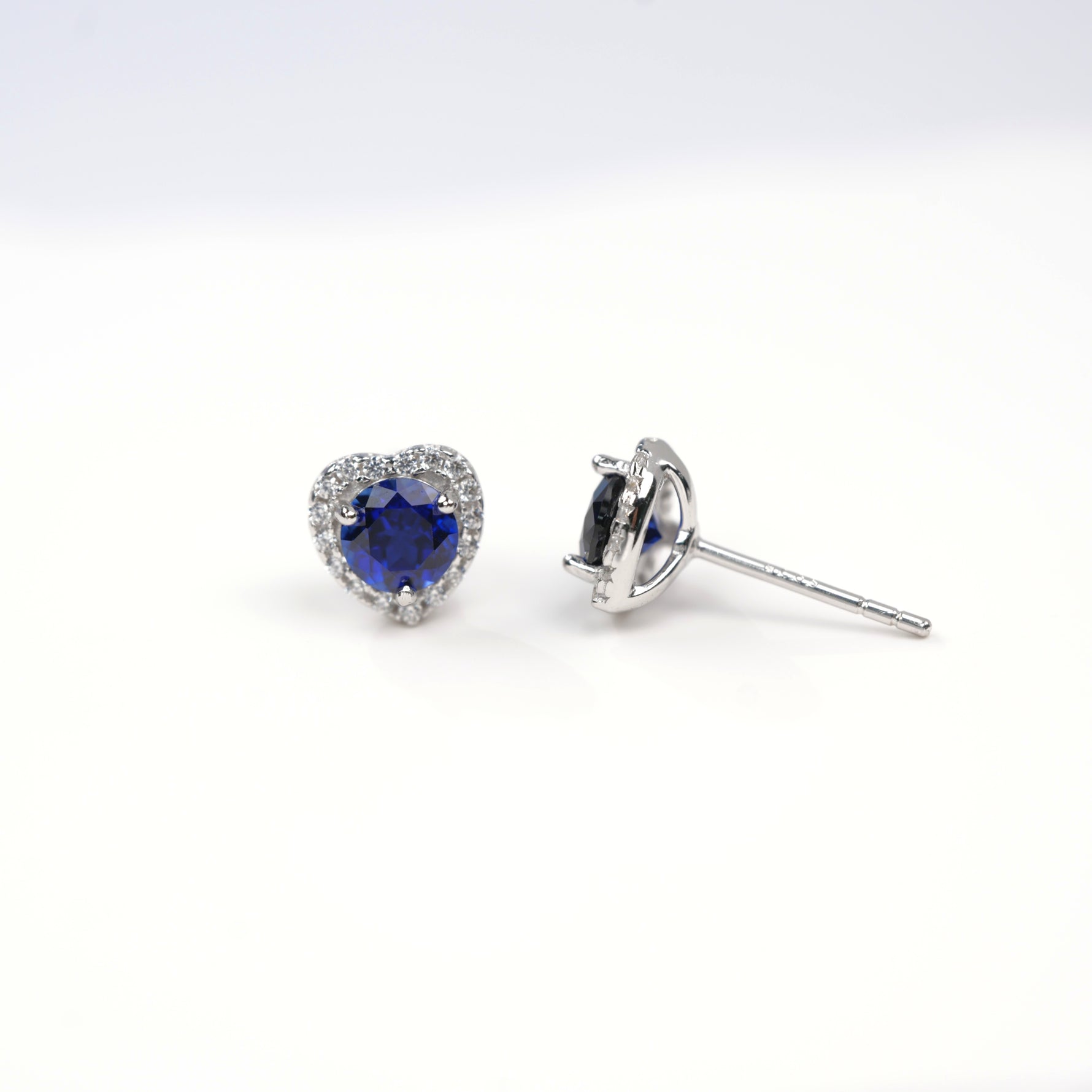 Heart-shaped blue gemstone earrings on a white background