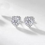 Heart-shaped diamond earrings on a light gray background