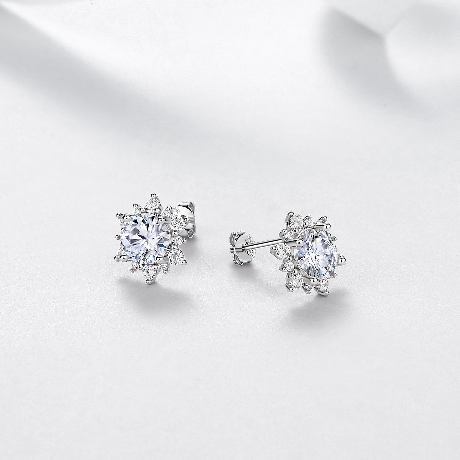 Pair of round moissanite halo stud earrings at an angle